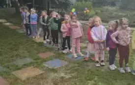 Dzieci stoją jeden za drugim w ogrodzie przedszkolnym.