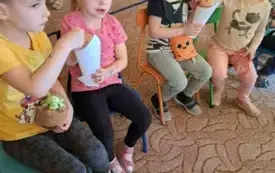 Dzieci siedzą na krzesełkach jedzą popcorn
