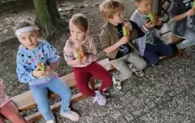 Dzieci siedzą na ławeczce pod altanką w ogrodzie przedszkolnym