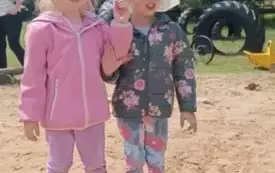 Dziewczynki stoją w piaskownicy.