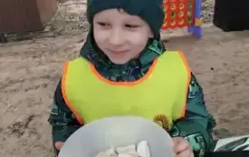 Chłopiec siedzi z talerzem kiełbasy