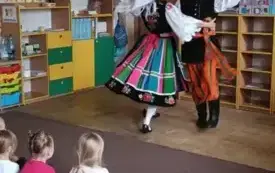Pan z panią przebrani w stroje łowickie tańczą.
