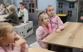 Dzieci siedzą na krzesełkach w muzeum