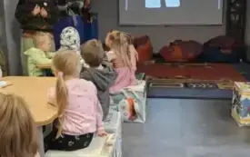 Dzieci siedzą w muzeum i słuchają Panią