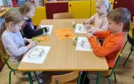 Dzieci wyklejają dynię.  