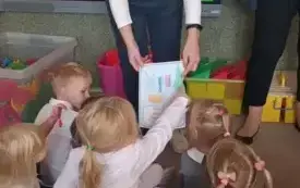NAuczycielka pokazuje dzieciom obrazek z przyborami higienicznymi