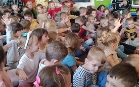 Dzieci siedzą na dywanie i słuchają koncertu
