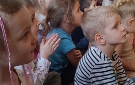 Dzieci siedzą na dywanie i słuchają koncertu