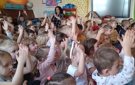 Dzieci siedzą na dywanie i klaszczą
