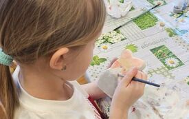 Dziewczynka maluje farbami figurke ceramiczną