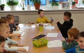 Dzieci wykonują prace plastyczne przy stoliku