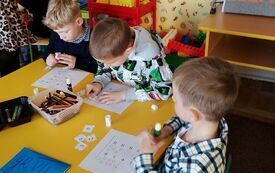 Dzieci rozwiązują zadania przy stoliku