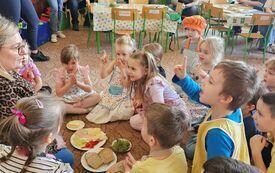 Zdjęcie nauczycielki z dziećmi na dywanie ze zdrową żywnością