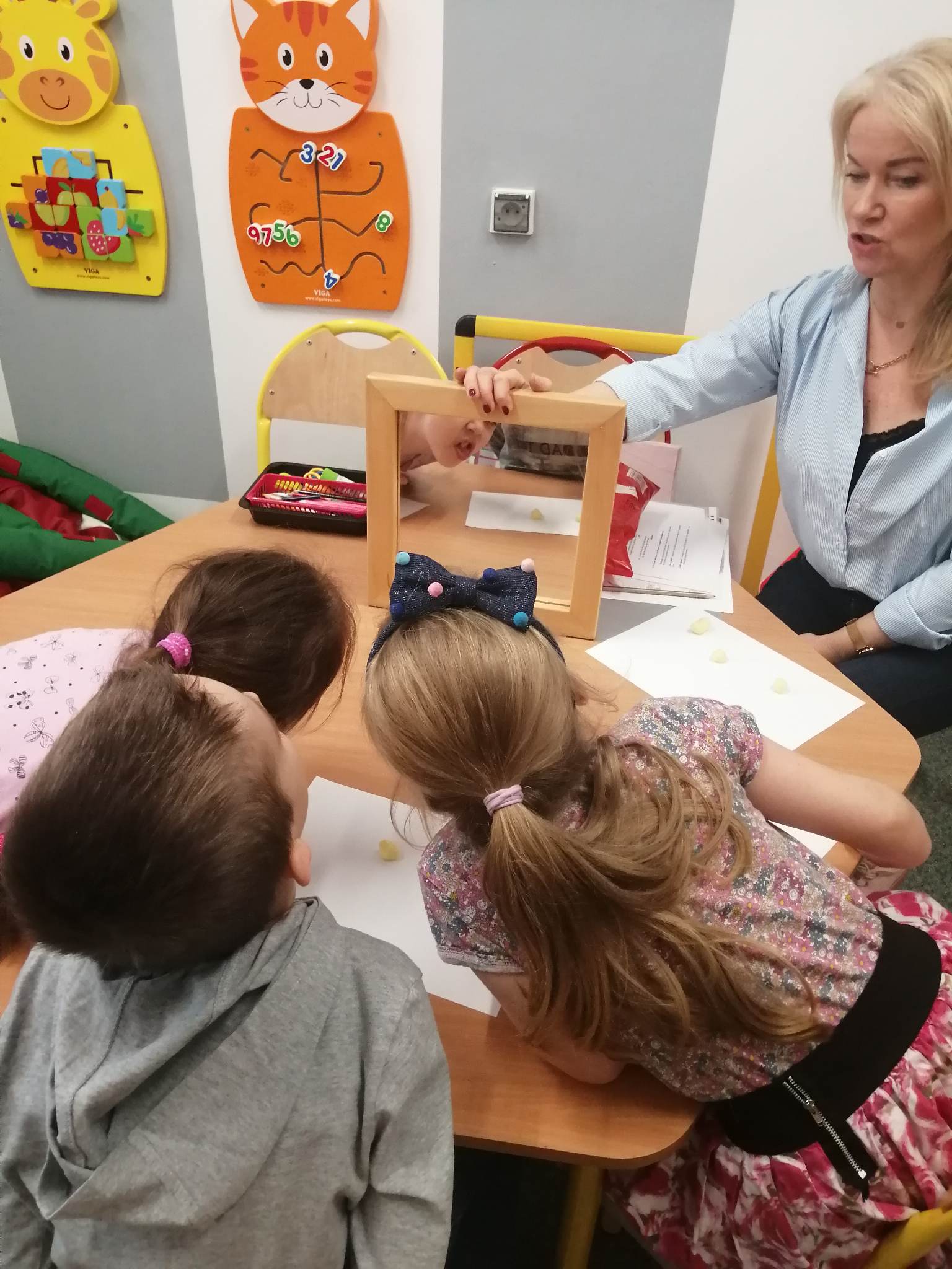 Zajęcia z logopedą. Dzieci patrzą w lusterko. Wykonują ćwiczenia.