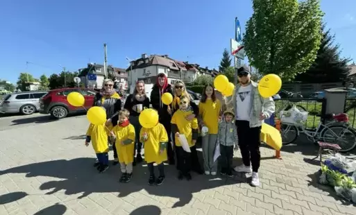 Dzieci wraz z rodzicami stoją ,uśmiechają się .