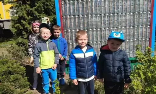 Dzieci stoją w ogrodzie przedszkolnym.