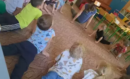 Dzieci leżą na dywanie i wyciągają głowy do góry
