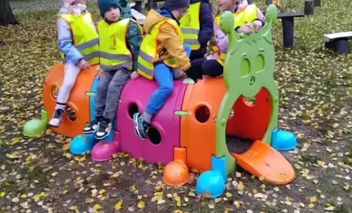 Dzieci siedzą na kolorowej gąsienicy.