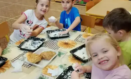 Dzieci siedzą przy stoliku. Wyrabiają masę solną