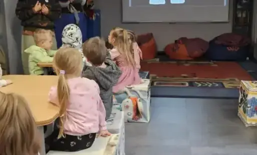 Dzieci siedzą w muzeum i słuchają Pani