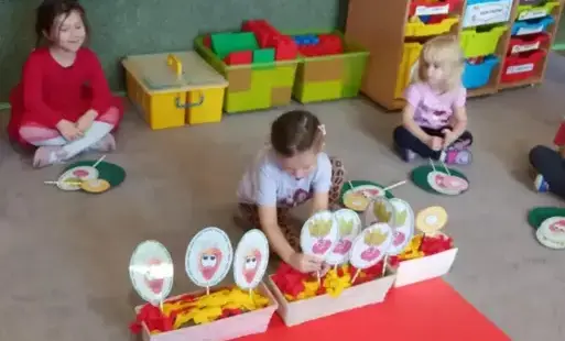 Dziewczynka kładzie znaczek warzywa na talerz.