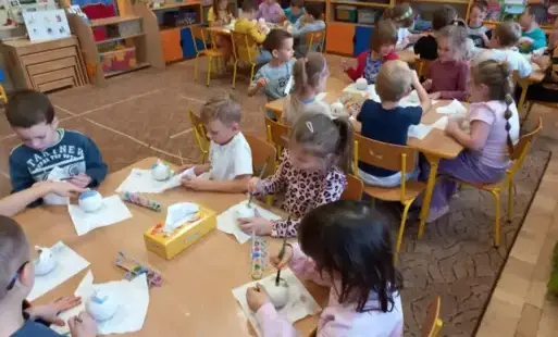Dzieci wykonują bombki. Siedzą przy stolikach.