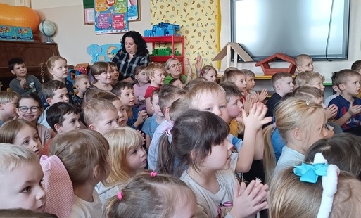 Dzieci siedzą na dywanie i słuchają koncertu