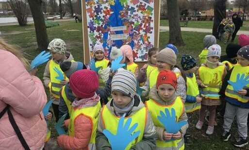 Dzieci stoją przed plakatem ,uśmiechają się .