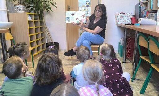 Dzieci słuchają czytanej bajki przez Panią Bibliotekarkę