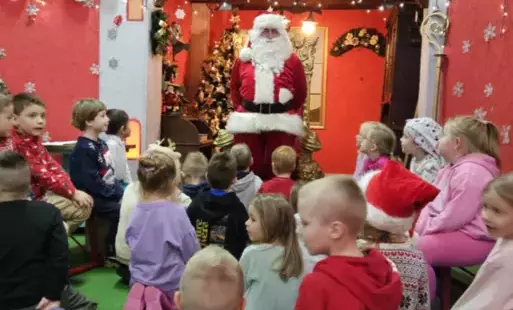 Dzieci siedzą słuchając Świętego Mikołaja